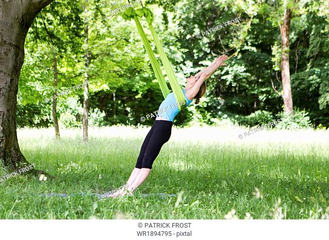 Young woman does stretching exercises with rubber band, Munich, Bavaria, Germany
