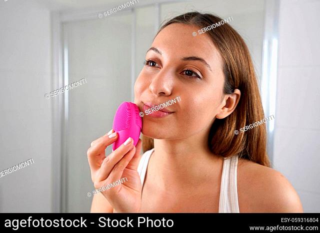 Close up of young woman cleaning skin with silicon brush ultrasonic in the bathroom