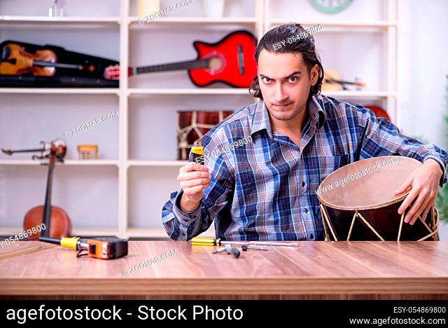 Young handsome repairman repairing drum