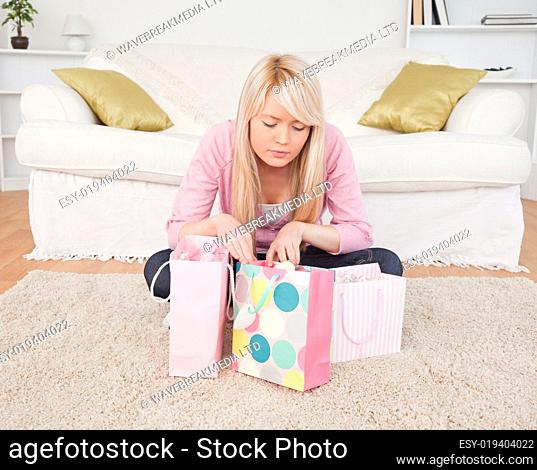 Blonde woman sitting in the living-room with her shopping bags