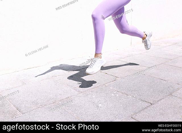 Female athlete jogging on footpath during sunny day