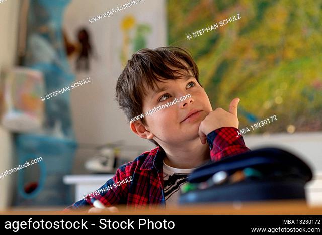A boy in homeschooling looks up at the ceiling, smiling