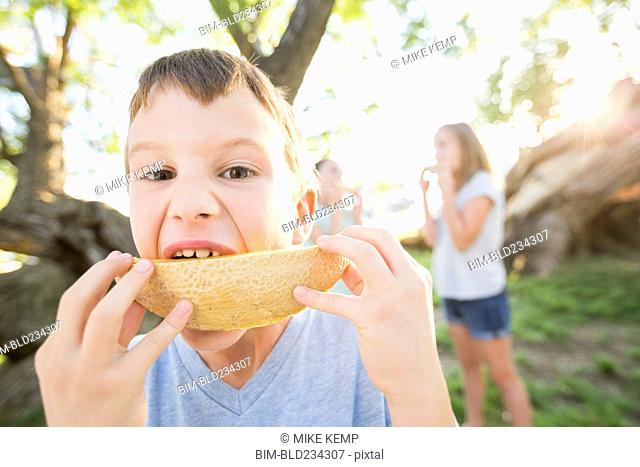 Caucasian boy eating cantaloupe