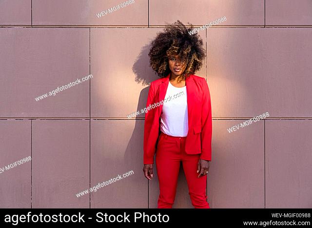 Mid adult woman standing standing against brown wall