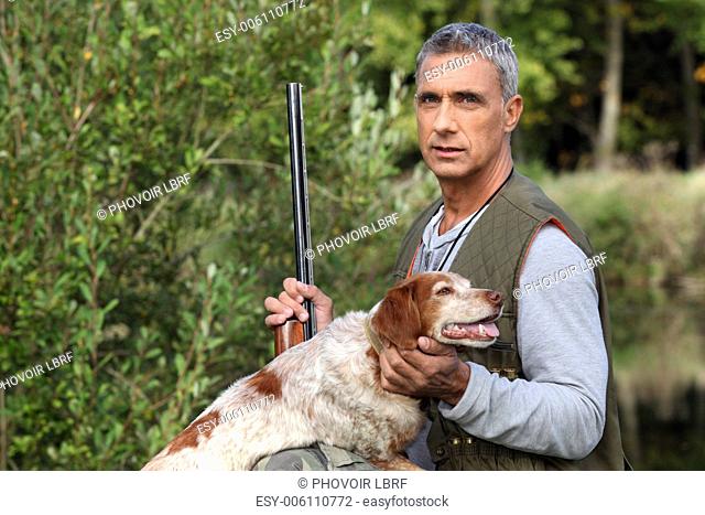 hunter taking a rifle and caressing a hunt dog