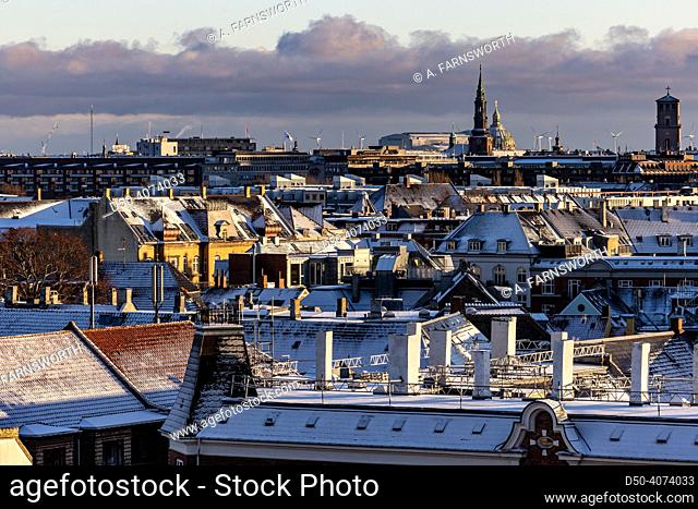 Copenhagen, Denmark Snow covers the rooftops of the city skyline, church spires, and wind turbines