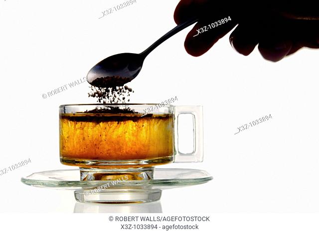 Instant coffee added to water in a glass cup