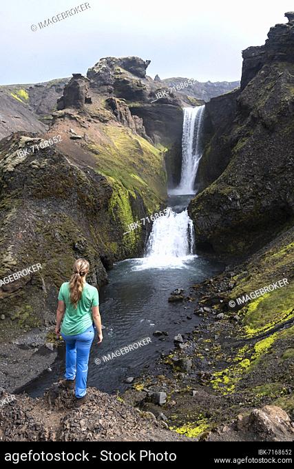 Hiker in front of waterfall in a gorge, landscape at Fimmvörðuháls hiking trail, South Iceland, Iceland, Europe