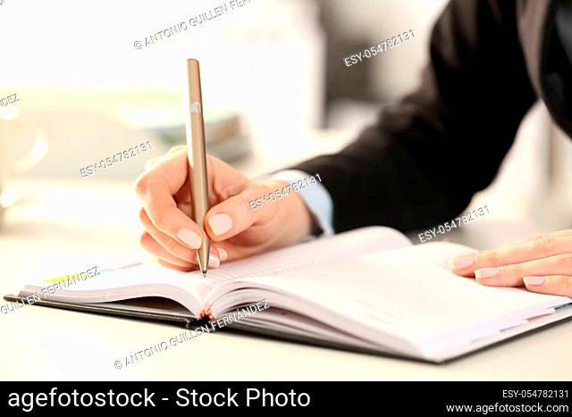 Close up of executive woman hands writing notes on agenda at the office