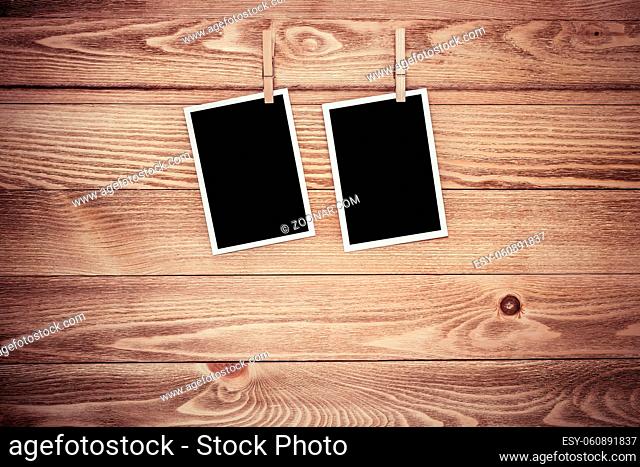 Blank photo frame hanging on rope on wooden textured background, 3D rendering