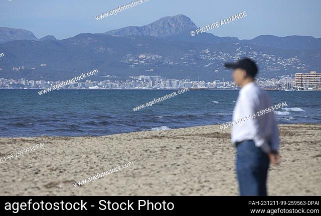 11 December 2023, Spain, Palma: A man gazes at the horizon on Arenal beach on a sunny day with a record temperature of 24 degrees