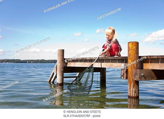 Girl fishing with net in lake
