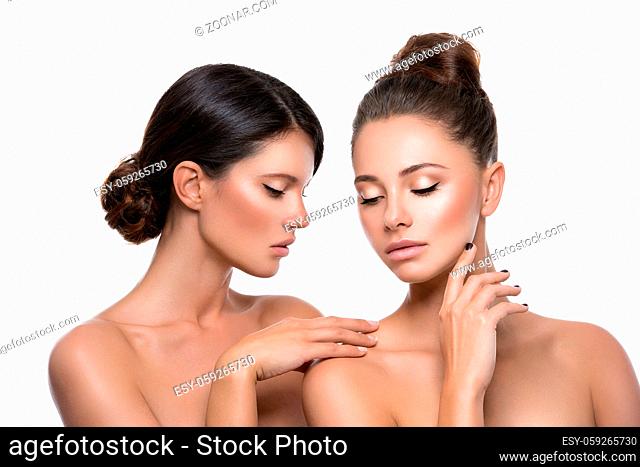 Two beautiful young women with perfect skin. Isolated over white background. Beauty shot. Copy space