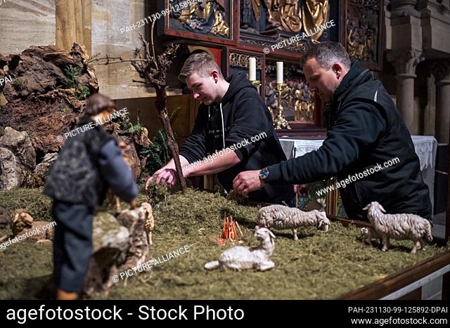 PRODUCTION - 29 November 2023, Bavaria, Bamberg: Marco Saffer (l) and sacristan Sebastian Dornheim (r) cover the floor of the nativity scene with moss