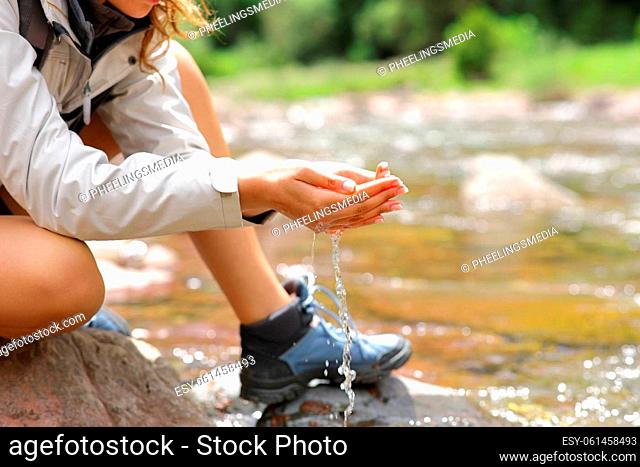 Close up of a trekker with cupped hands catching water from river in the mountain