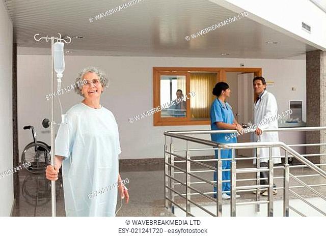 Laughing woman standing in the hallway holding a drip in her hands