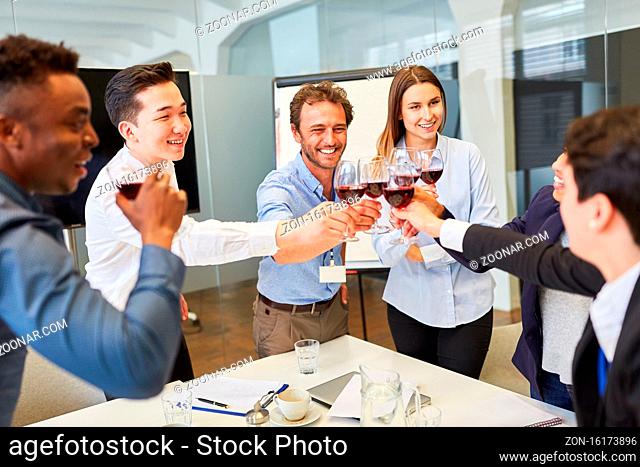 Junges Start-Up Team beim Anstoßen mit einem Glas Rotwein auf einer Betriebsfeier