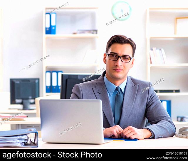 The handsome businessman employee sitting at his desk in office