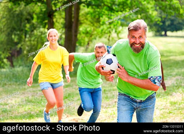 Junges Team spielt mit einem Fußball auf einem Teambuilding Workshop im Park