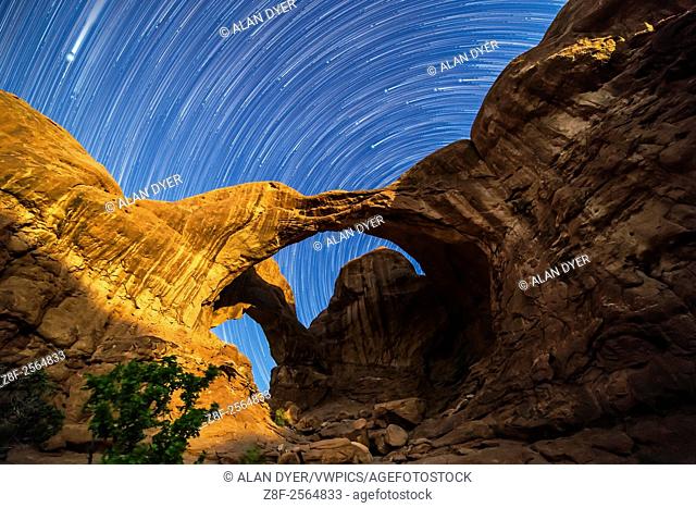 Circumpolar star trails spinning behind Double Arch at Arches National Park, Utah, as the waning gibbous Moon lights the arches toward the end of the sequence