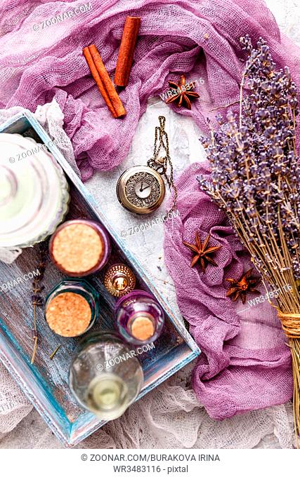 Lavender background with bouquet and twigs of dry lavender, bottle with cosmetic oil, perfume bottle, vintage pocket watch, cinnamon sticks