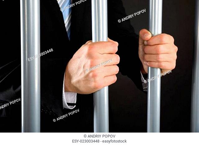 Close-up Of Businessman Holding Bars In Jail