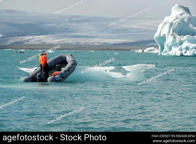 11 August 2022, Iceland, Jökulsarlon: A small boat pushes away a chunk of ice in Jökulsárlón, a glacial lagoon in southeastern Iceland