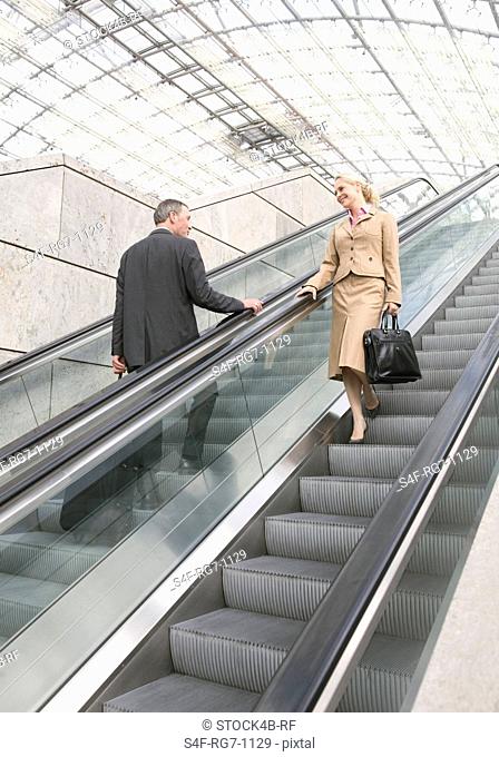 Businessman and businesswoman flirting on escalator