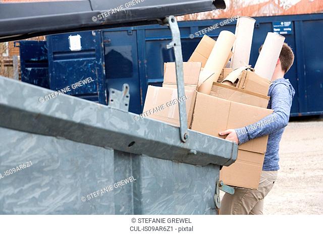 Teenage boy carrying cardboard waste to recycling bin