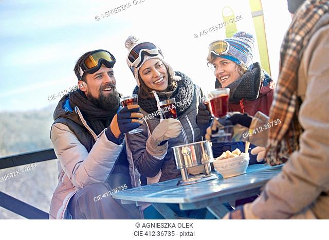 Skier friends drinking and eating at balcony table apres-ski