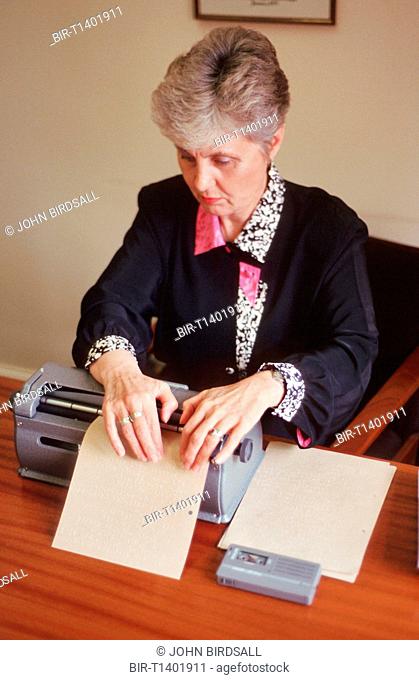 Woman with visual impairment sitting at desk using Braille typewriter