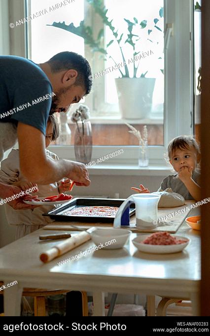 Happy father and son preparing pizza together at home