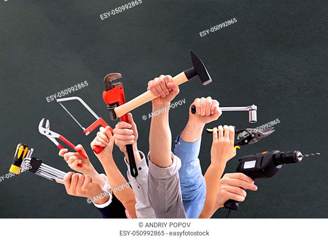 Close-up Of People's Hand Holding Carpentry Tools Against Black Background
