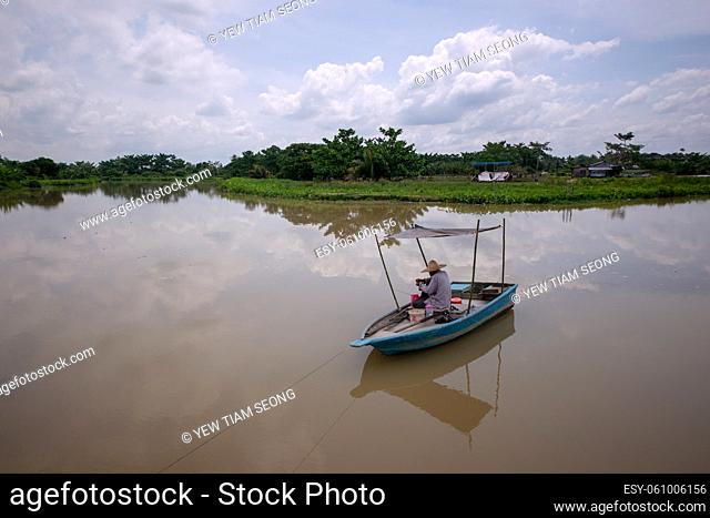 Seberang Perai, Penang, Malaysia - Circa Jun 2018: Angler fishing at calm river under blue sky