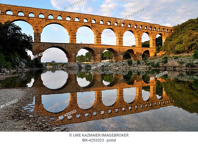 Roman aqueduct Pont du Gard reflected in the Gardon river in the evening, Remoulins, Provence, Southern France, France, Europe