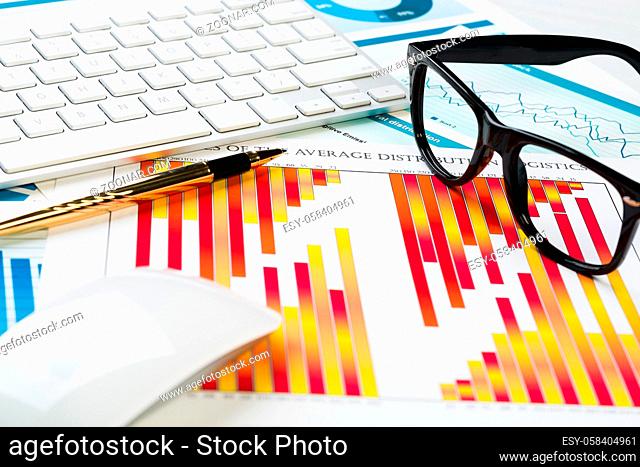 Business workplace with keyboard glasses and financial documents on table