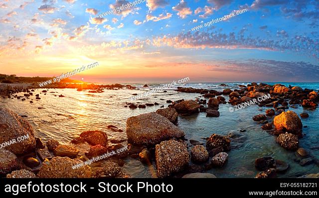 Sunset view from stony beach. Summer coastline (Greece, Zakynthos, Alykes, Ionian Sea)