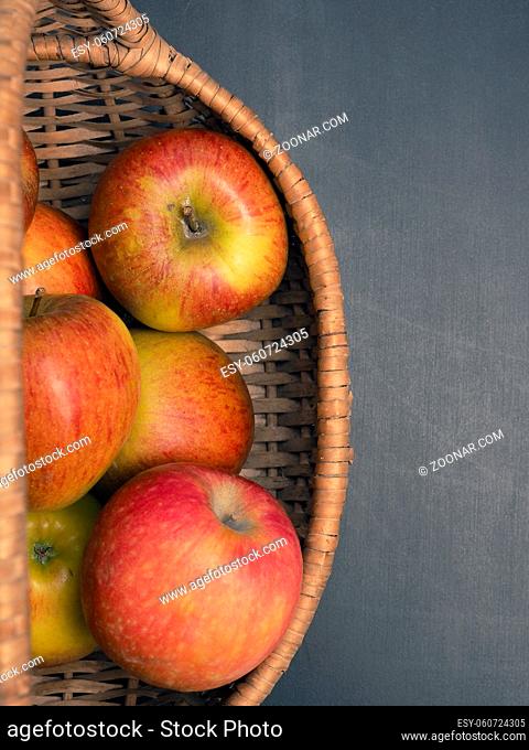 Fresh organic apples in a basket on a dark background, view from above
