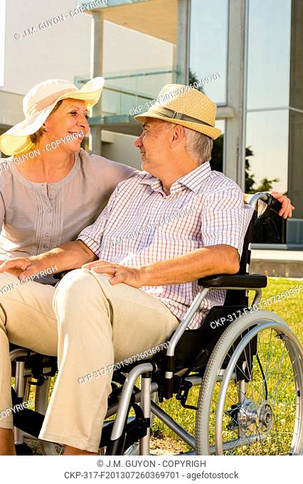 Retirement disabled man with wife sitting outdoors