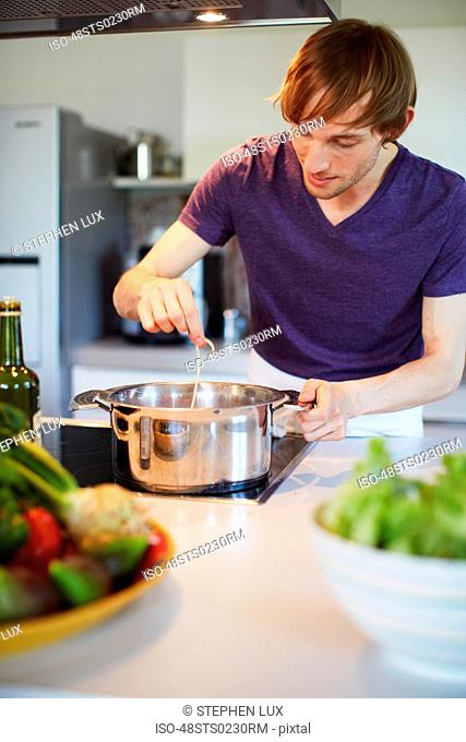 Man tasting pasta in kitchen