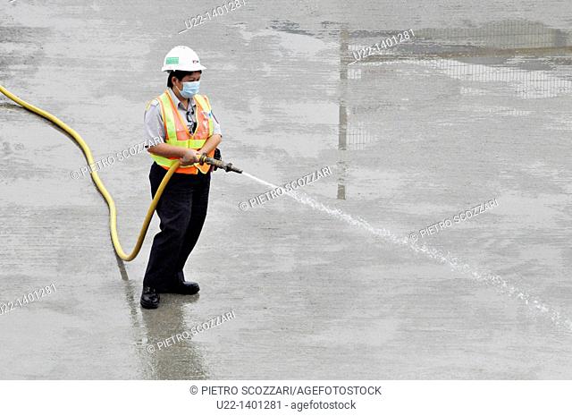 Hong Kong: a man at work watering the pavement by the construction of the new pier on Victoria Harbour, in Central