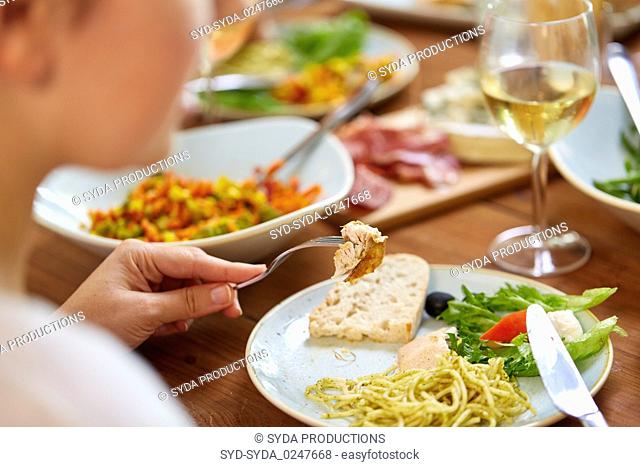 hands of woman eating pasta with chicken