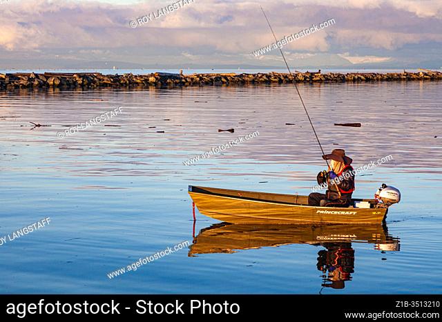 Lone fisherman in an aluminum boat at sunrise in Steveston Harbour British Columbia Canada