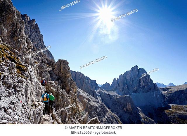 Hiker ascending the Alpinisteig climbing route, currently on Elferscharte Mountain, looking towards Zwoelferkofel Mountain, Alta Pusteria, Sesto, Dolomites