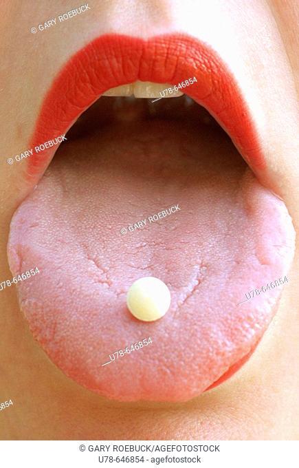 Woman with vitamin pill on tongue