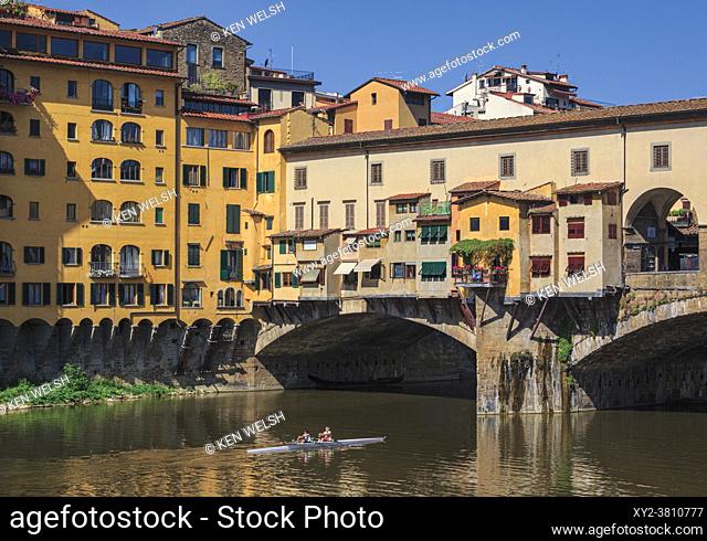 Florence, Florence Province, Tuscany, Italy. Scullers passing under the Ponte Vecchio, or Old Bridge, on the Arno River. The historic centre of Florence is a...