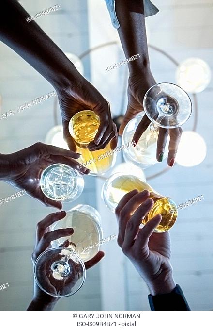 Group of friends making a toast, upward view of hands holding glasses