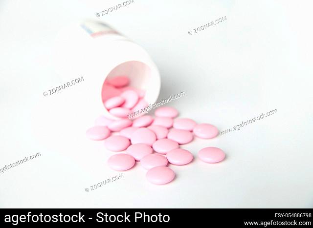 Close-up of bottle of pink tablets scattered on table