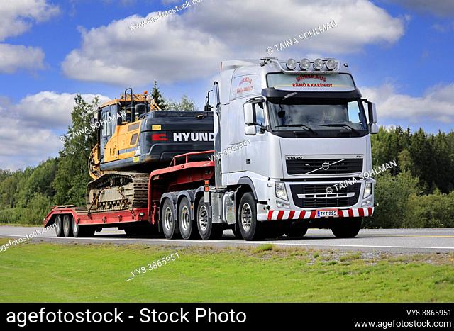 Volvo FH truck of Murskaus Rämö & Karen Oy hauls Huyndai HX 300L excavator on trailer as wide load along highway 2. Forssa, Finland. August 28, 2020