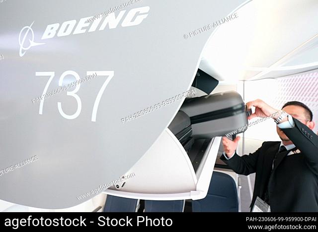 06 June 2023, Hamburg: An employee pulls a suitcase from the new luggage rack of a Boeing 737 at the booth of aircraft manufacturer Boeing at the Aircraft...